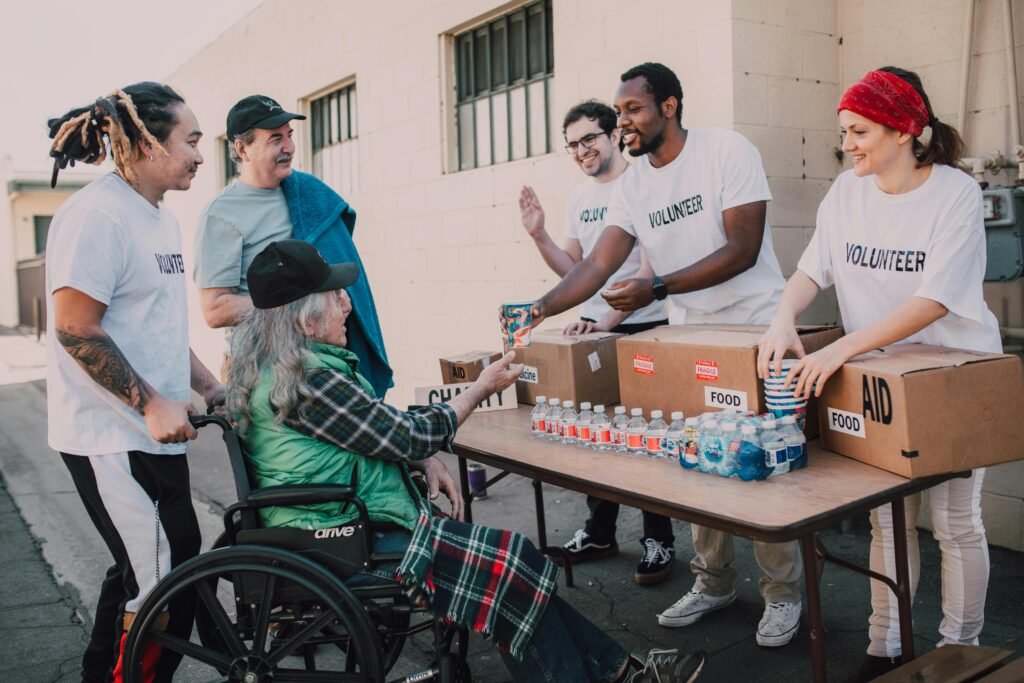 Michael esposito Volunteers distribute bottled water and supplies to diverse individuals in an outdoor setting, showcasing community support.