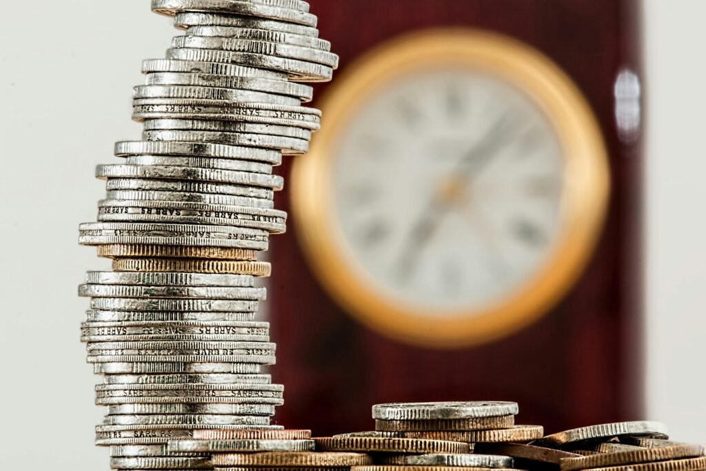 A close-up image of stacked coins with a blurred clock, symbolizing time and money relationship. Understanding the Power of Compound Interest